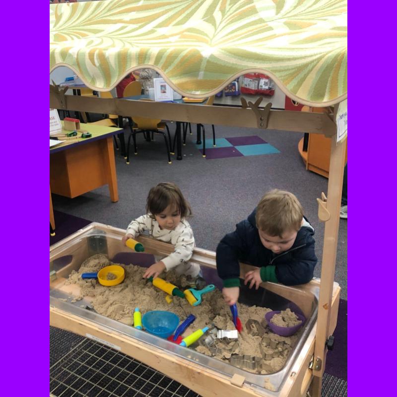 two children playing at a sand table