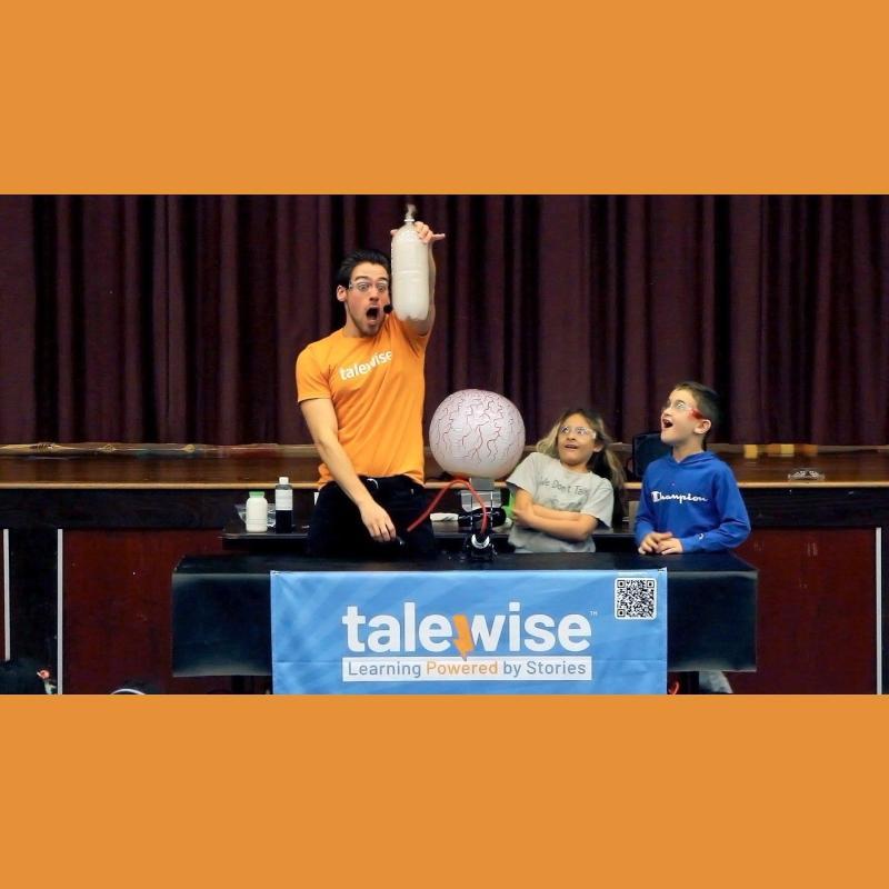 Performer holding science experiment with two children watching